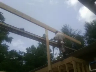 Carpenter setting a ridge beam over a new addition frame — Ice Dam Removal by Roofing Brothers in Paullina