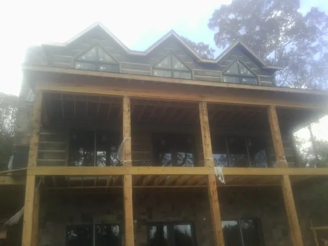 Dormers and porch framing on a large log home under construction — Roof Coating work by our crew in Paullina