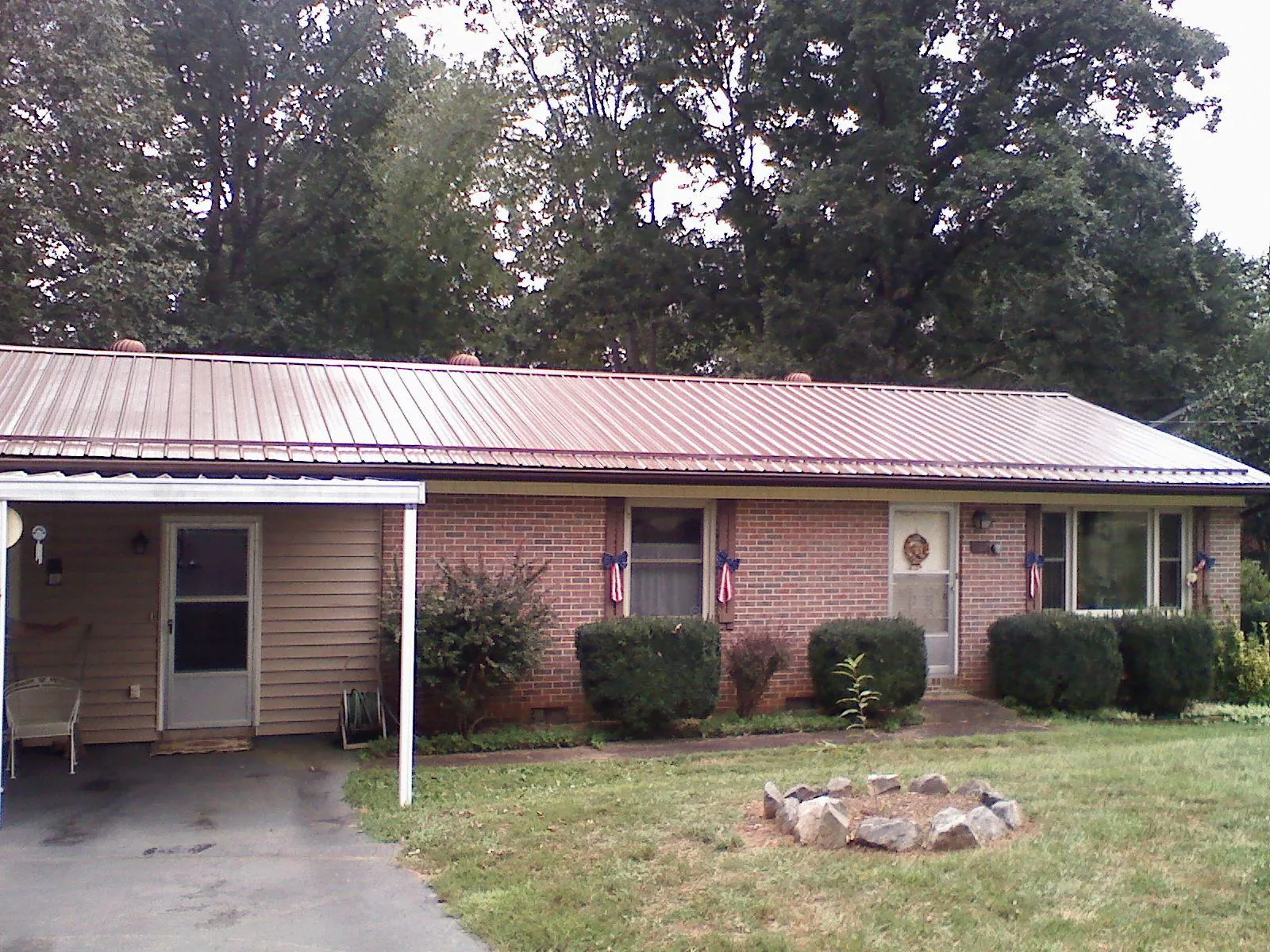 Bronze metal roof and carport on a brick ranch home — Roof Repair work by our crew in Paullina