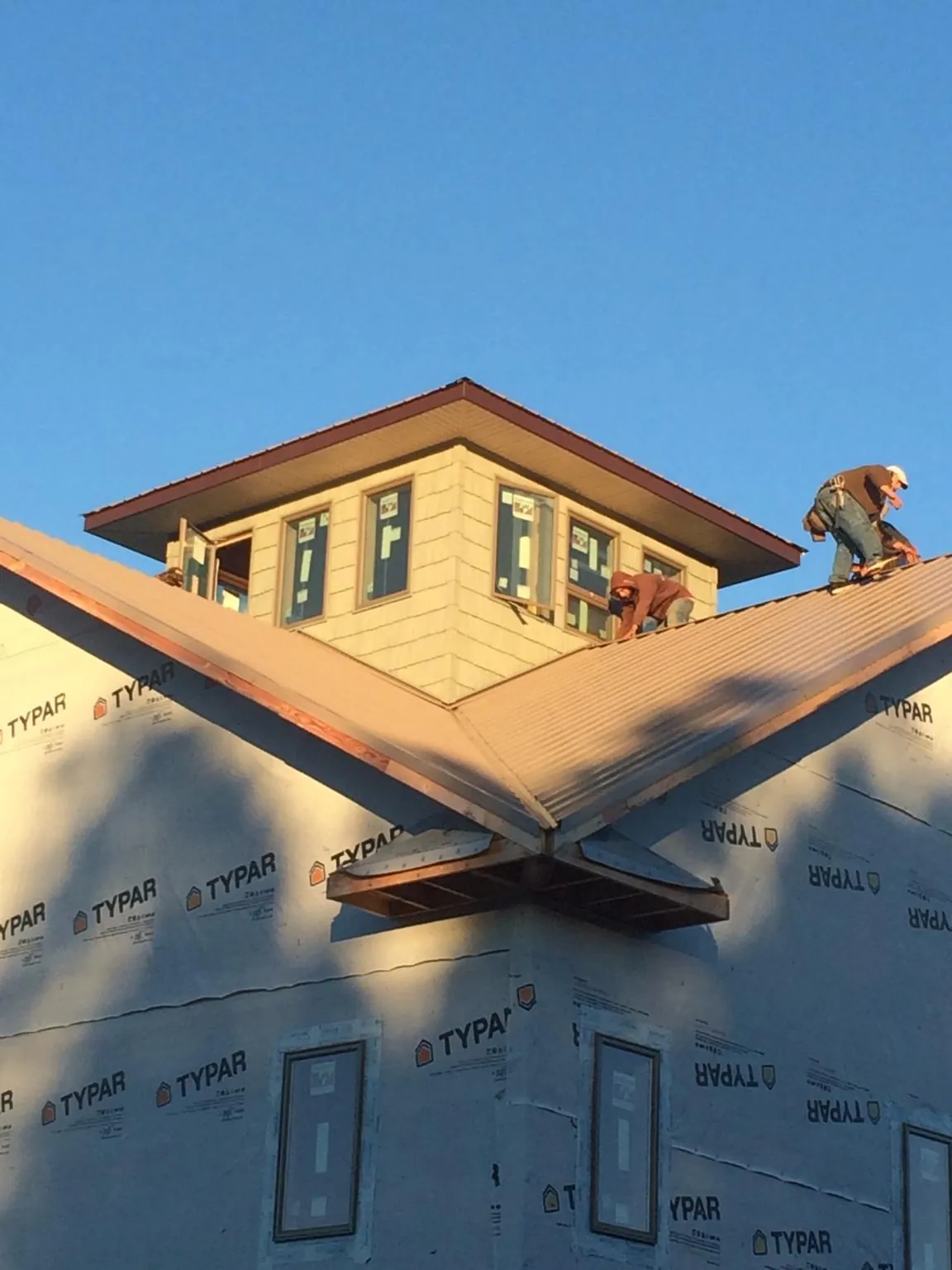 Roofers working around a rooftop cupola on a new metal roof at sunset — Roof Waterproofing in Paullina by Roofing Brothers